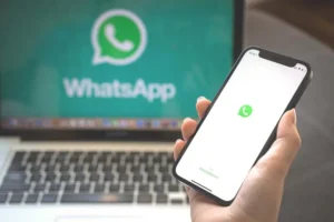 Handy und Notebook zeigen das WhatsApp Logo auf dem Bildschirm